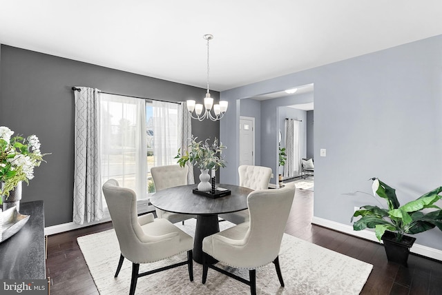 dining area featuring dark wood finished floors, baseboards, and an inviting chandelier