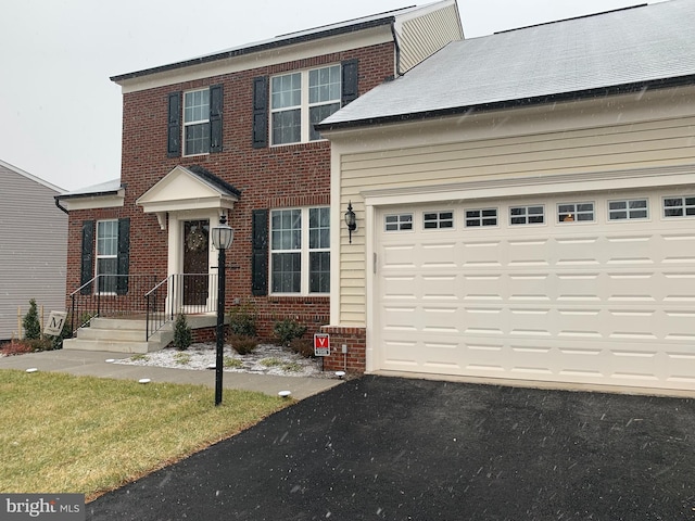 view of front of home featuring a garage, brick siding, and aphalt driveway