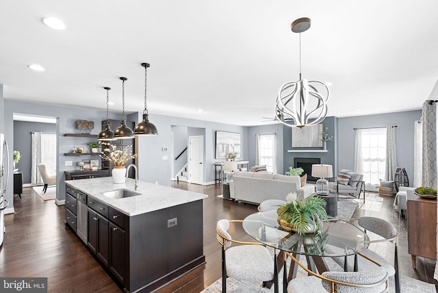 kitchen featuring a wealth of natural light, a sink, an inviting chandelier, a fireplace, and dark wood-style flooring