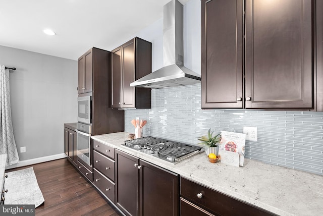 kitchen featuring dark brown cabinets, stainless steel appliances, wall chimney exhaust hood, and dark wood-type flooring