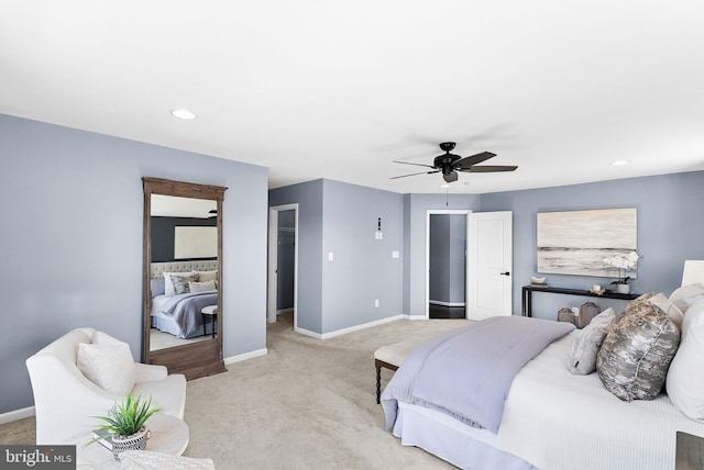 bedroom with ceiling fan, baseboards, light carpet, and a walk in closet