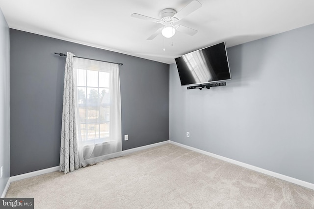 carpeted spare room featuring baseboards and ceiling fan