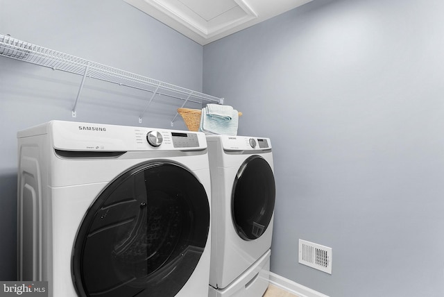 clothes washing area with laundry area, washing machine and dryer, and visible vents