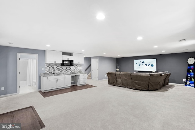 carpeted living area with a sink, visible vents, baseboards, and recessed lighting