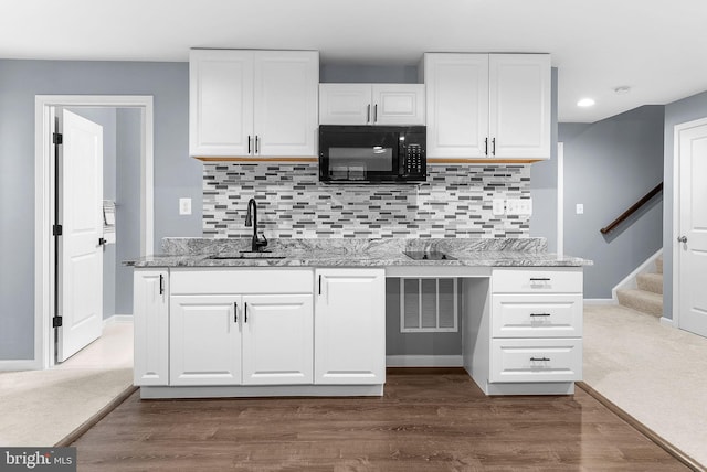 kitchen featuring a sink, dark wood-style flooring, white cabinets, and black microwave