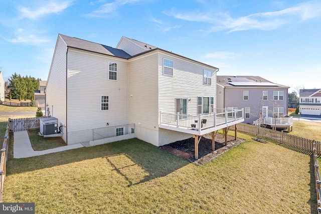 rear view of house featuring a wooden deck, central AC unit, a lawn, and a fenced backyard