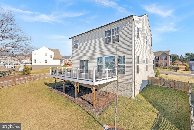 rear view of property with a lawn, a wooden deck, and a fenced backyard