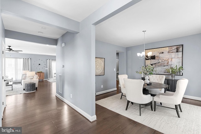 dining area featuring ceiling fan with notable chandelier, baseboards, and dark wood-style flooring