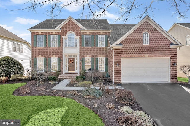 view of front of home with driveway, a shingled roof, a front lawn, and brick siding