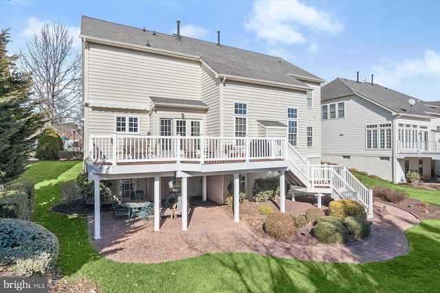 back of house featuring stairs, a deck, a lawn, and a patio