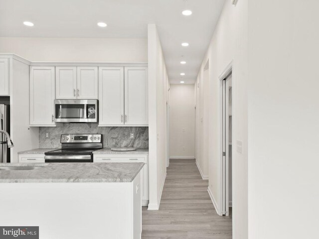 2 Bowers Dr Unit 101, Ocean View, DE 19970 - kitchen featuring stainless steel appliances, recessed lighting, light wood-style flooring, tasteful backsplash, and light stone counters