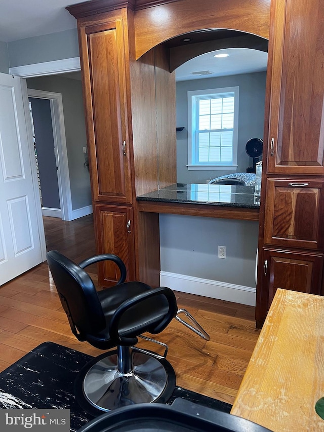 interior space with arched walkways, baseboards, and wood finished floors