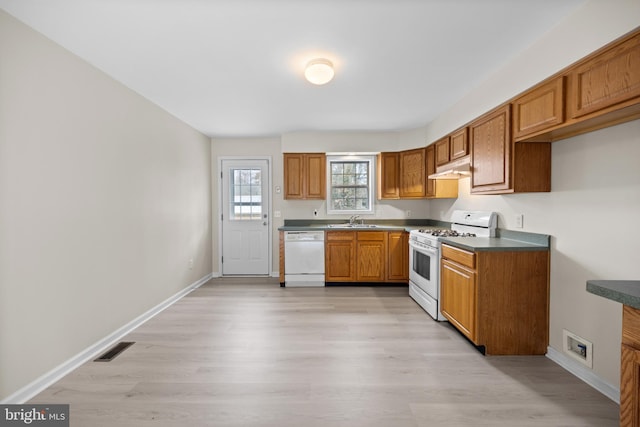 kitchen with white appliances, brown cabinetry, visible vents, and baseboards