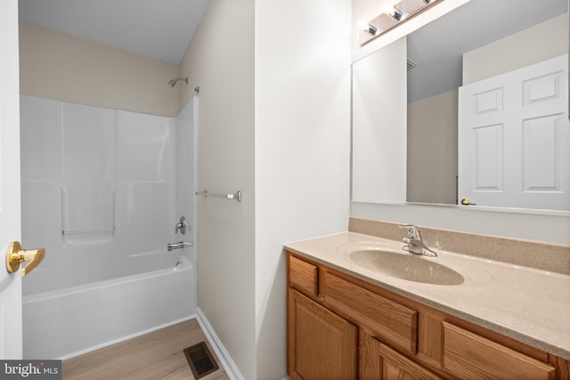 bathroom with visible vents, shower / bathing tub combination, vanity, wood finished floors, and baseboards