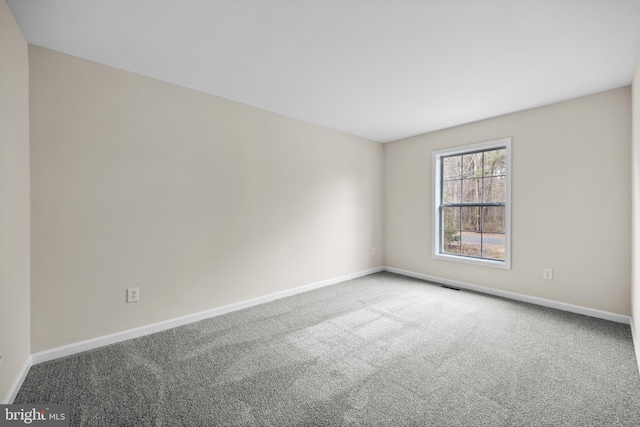 carpeted spare room featuring baseboards