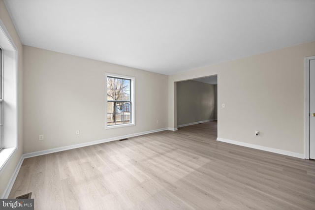 spare room featuring light wood-style floors, visible vents, and baseboards