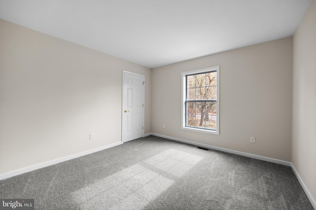 empty room featuring carpet floors, baseboards, and visible vents