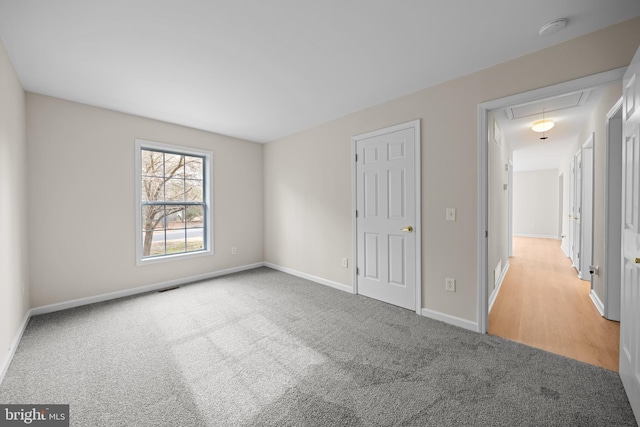 unfurnished bedroom featuring carpet floors, attic access, visible vents, and baseboards