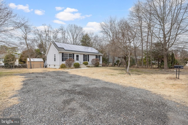 view of front of house featuring an outbuilding, roof mounted solar panels, and fence