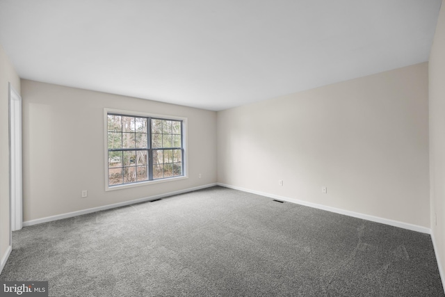 unfurnished room with carpet, visible vents, and baseboards