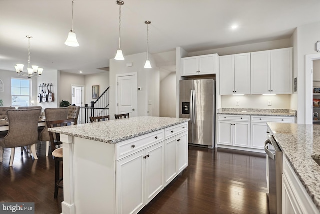 kitchen with dark wood-type flooring, a chandelier, hanging light fixtures, white cabinets, and stainless steel appliances