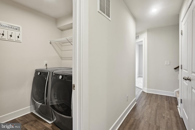 clothes washing area featuring washing machine and clothes dryer, laundry area, dark wood finished floors, and visible vents