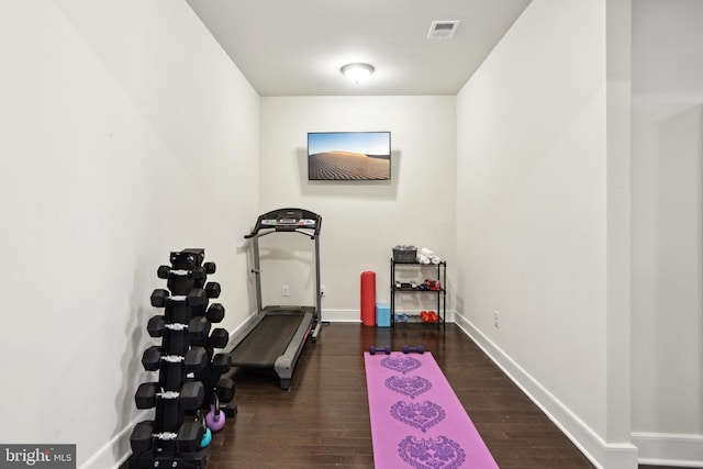 exercise room with visible vents, dark wood-type flooring, and baseboards