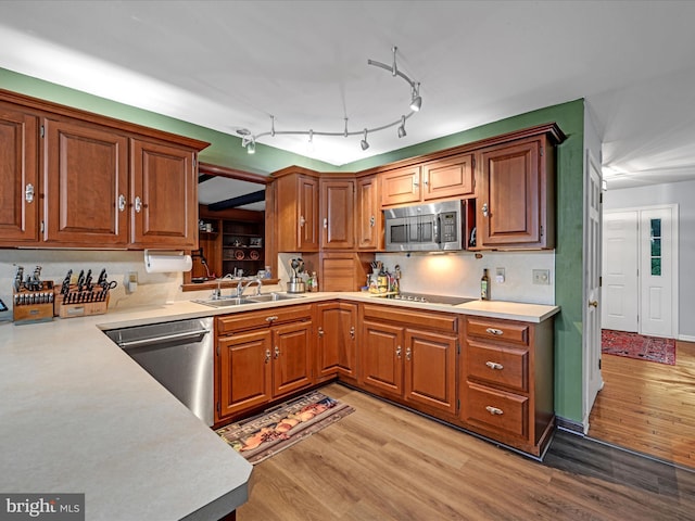 kitchen featuring light wood finished floors, light countertops, appliances with stainless steel finishes, and a sink