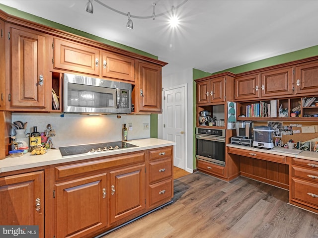 kitchen with light wood finished floors, stainless steel appliances, light countertops, and built in study area