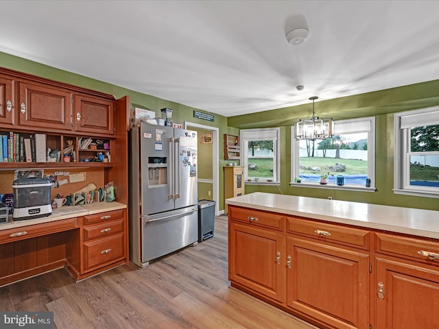 kitchen featuring light countertops, high quality fridge, brown cabinetry, and a wealth of natural light