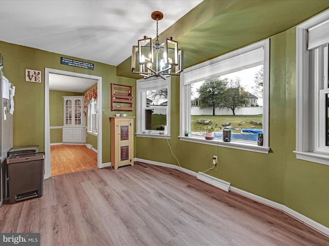 unfurnished dining area with an inviting chandelier, visible vents, baseboards, and wood finished floors