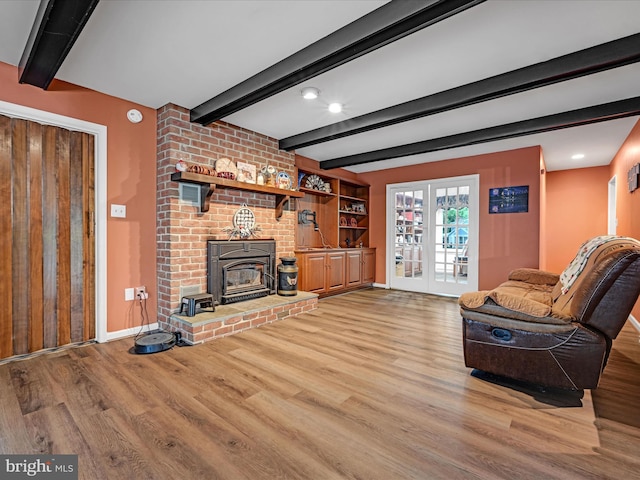 living room with beamed ceiling, light wood-style flooring, and baseboards