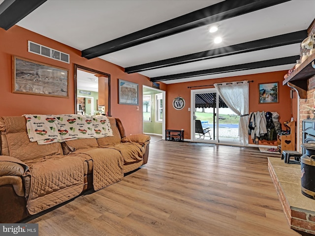 living room featuring beamed ceiling, wood finished floors, visible vents, and baseboards