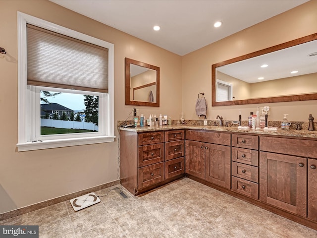 bathroom with double vanity, baseboards, a sink, and recessed lighting