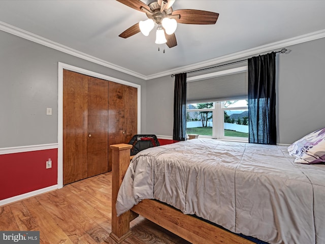 bedroom featuring baseboards, ceiling fan, wood finished floors, crown molding, and a closet