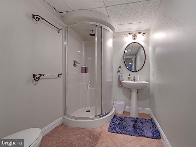 full bath featuring baseboards, toilet, tile patterned floors, a paneled ceiling, and a shower stall