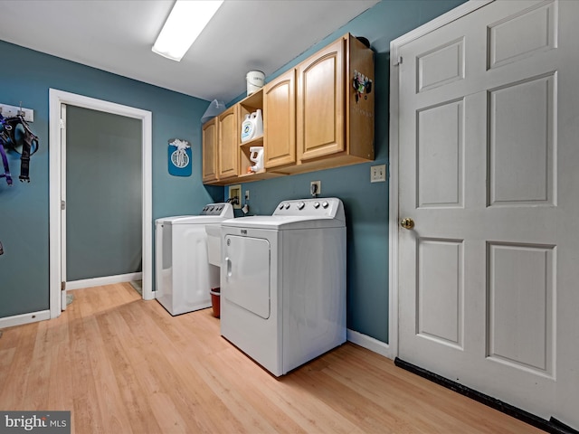 clothes washing area featuring separate washer and dryer, light wood-style flooring, cabinet space, and baseboards