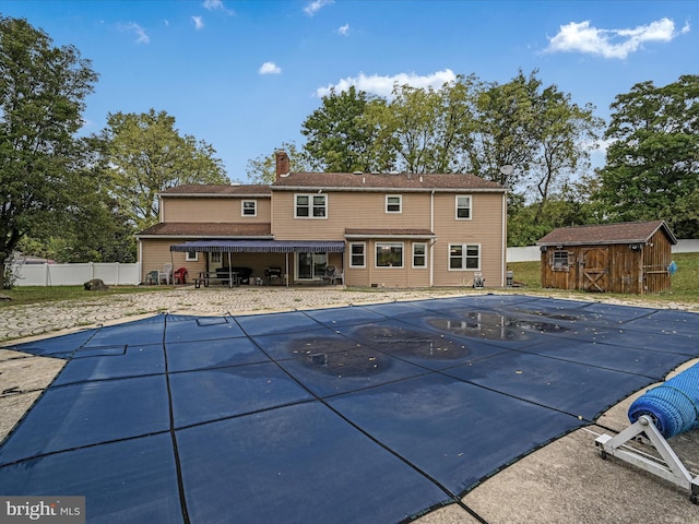 rear view of property with an outbuilding, a patio, a storage shed, fence, and a chimney