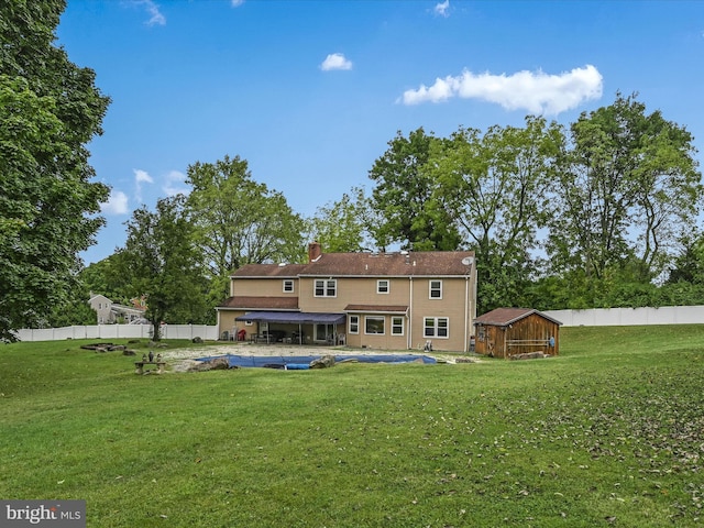 rear view of house with a fenced backyard, a chimney, a pool, and a yard