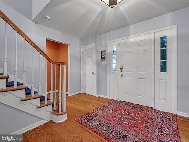 foyer featuring stairway, wood finished floors, and baseboards