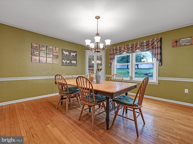 dining area featuring ornamental molding, a notable chandelier, light wood-style flooring, and baseboards