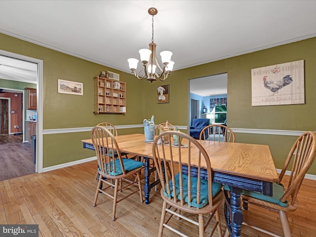 dining room with light wood-style floors, a notable chandelier, crown molding, and baseboards