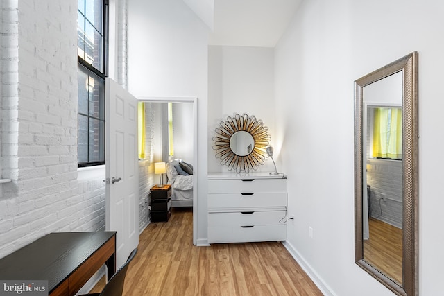 interior space featuring light wood-style floors, baseboards, and brick wall