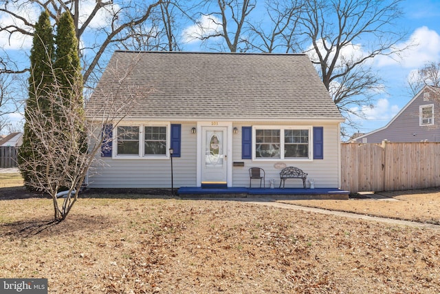 view of front facade with a shingled roof and fence