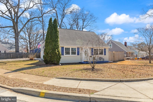 view of front of property with a front lawn, roof with shingles, and fence