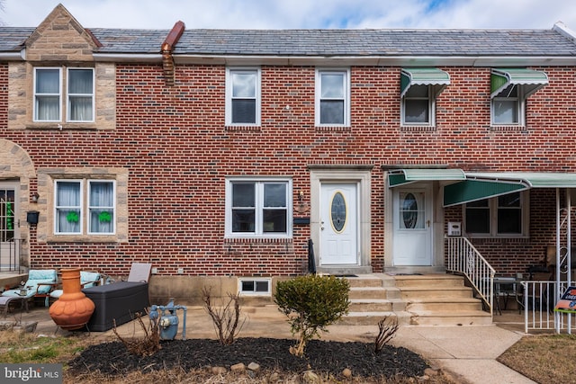 view of property featuring a high end roof and brick siding