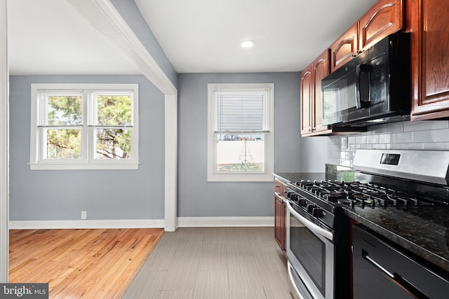 kitchen with tasteful backsplash, baseboards, dark stone countertops, appliances with stainless steel finishes, and light wood-style floors