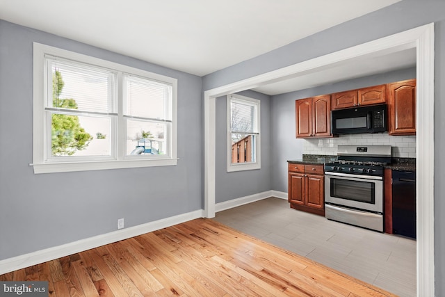 kitchen featuring baseboards, black appliances, dark countertops, tasteful backsplash, and light wood-type flooring