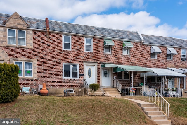 multi unit property with mansard roof, a high end roof, brick siding, and a front lawn