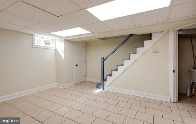 below grade area featuring stairway, baseboards, and a drop ceiling